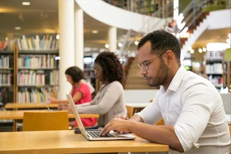 adults working on laptops at library tables