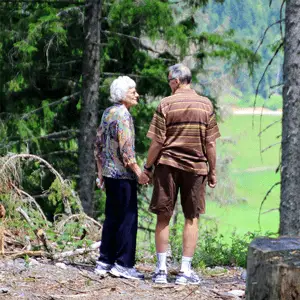 elderly couple holding hands in wooded area