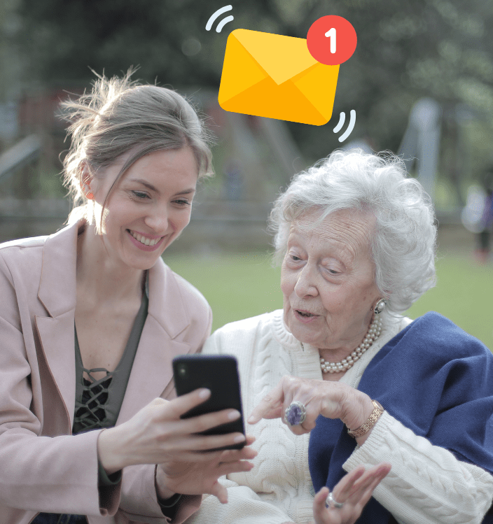 in a park, a woman is showing an older woman email on her phone
