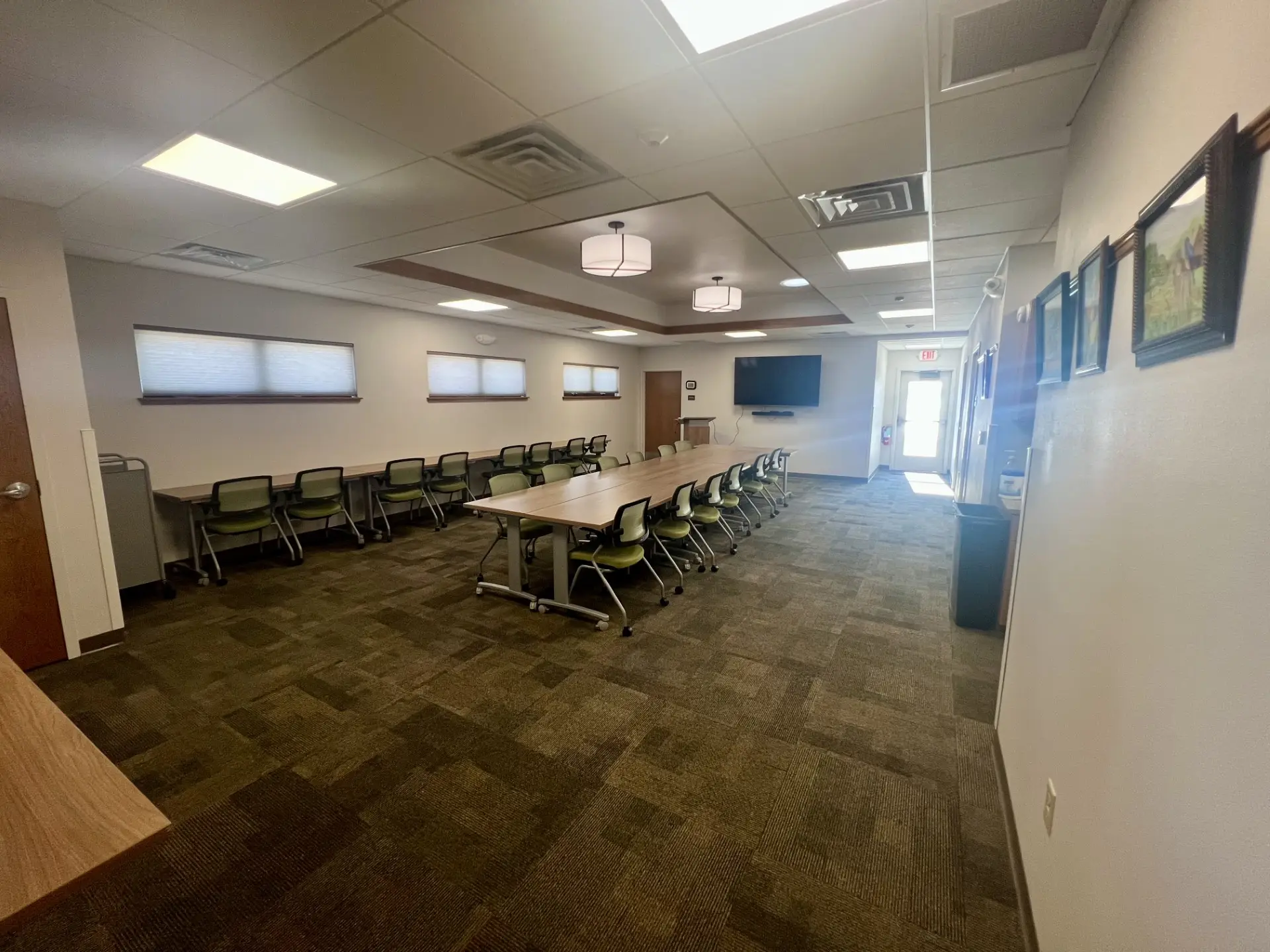 Zeller communitiy room with modular tables and chairs, large monitor on wall, small kitchen