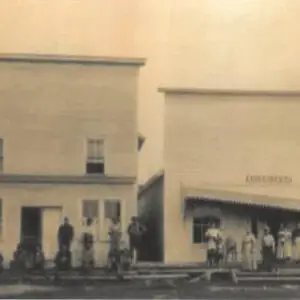 historic black and white photo of people in front of buildings on wooden sidewalks and stairs