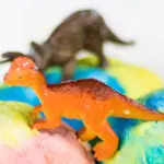 toy dinosaurs on pastel masses that appear to be ice cream or balls of play dough