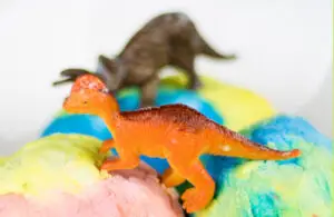 toy dinosaurs on pastel masses that appear to be ice cream or balls of play dough